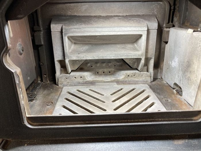 掃除を終えた薪ストーブの炉内。灰がすべて取り除かれ、ロストルとバッフル板、二次空気の穴まで地金が見えている