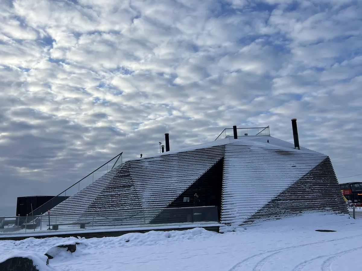 ヘルシンキ南端の海沿いに建つ公共サウナ。木のルーバーが斜めに立ち上がり、雪をかぶった屋根の上に人が歩ける階段がついている