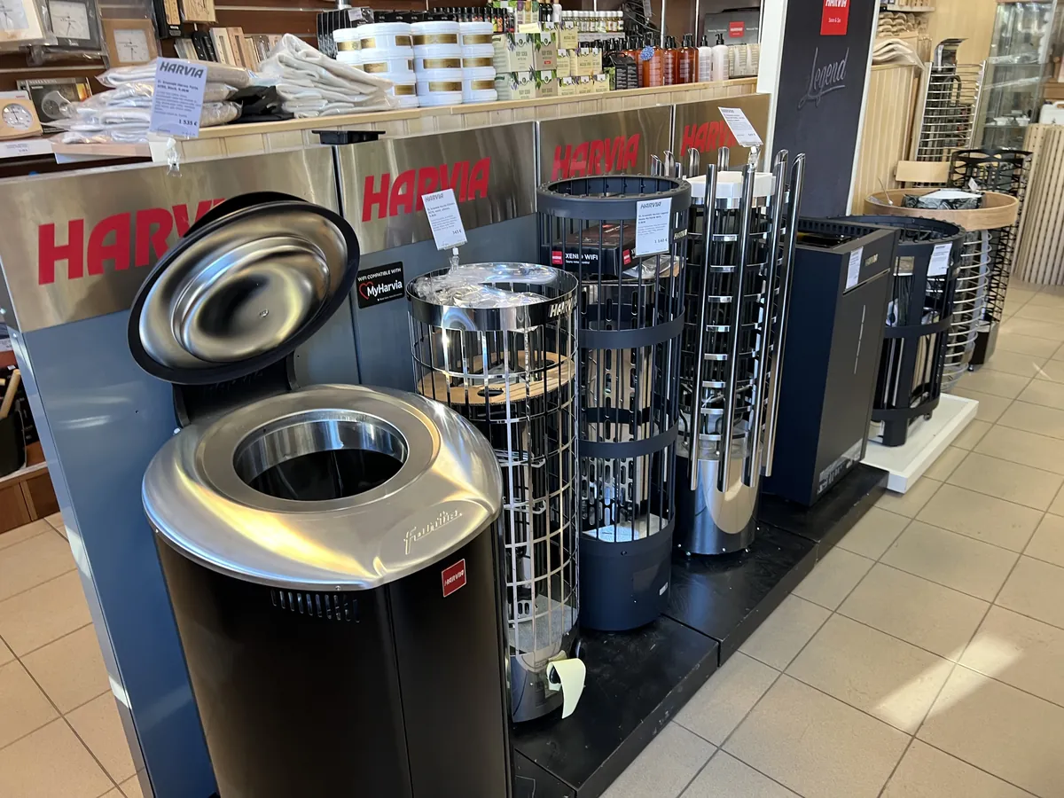 リトアニアのサウナ資材店の売り場。赤いHARVIAの看板の下に、電気サウナヒーターが数台並べて展示されている