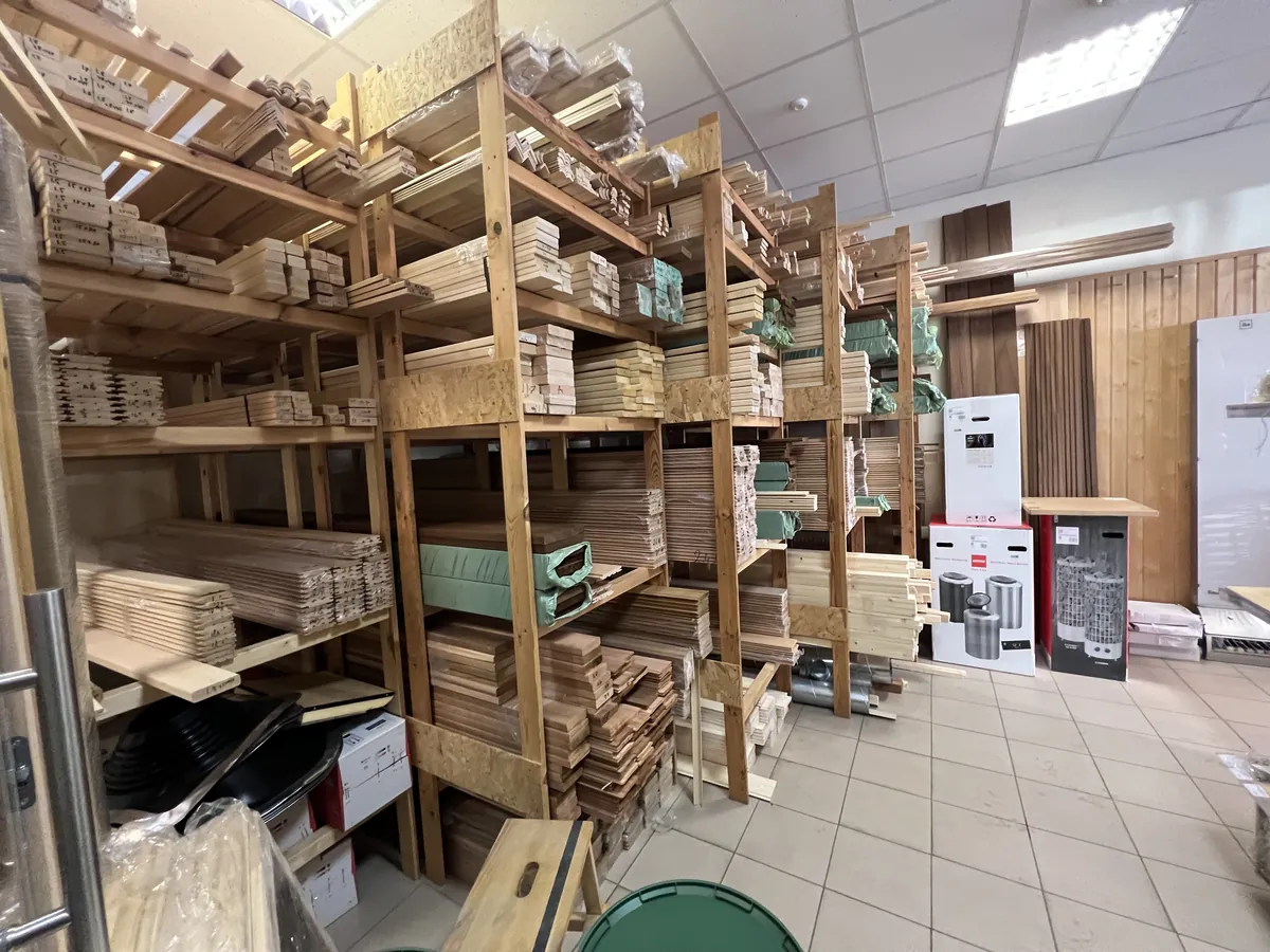 サウナ資材店の木材売り場。天井まである棚に、サウナ用の内装材とベンチ材が樹種ごとに並ぶ