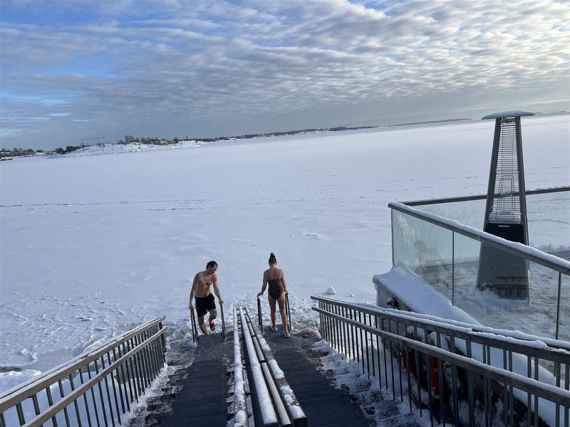 凍った海へ階段を下りていく、サウナ上がりの2人の後ろ姿