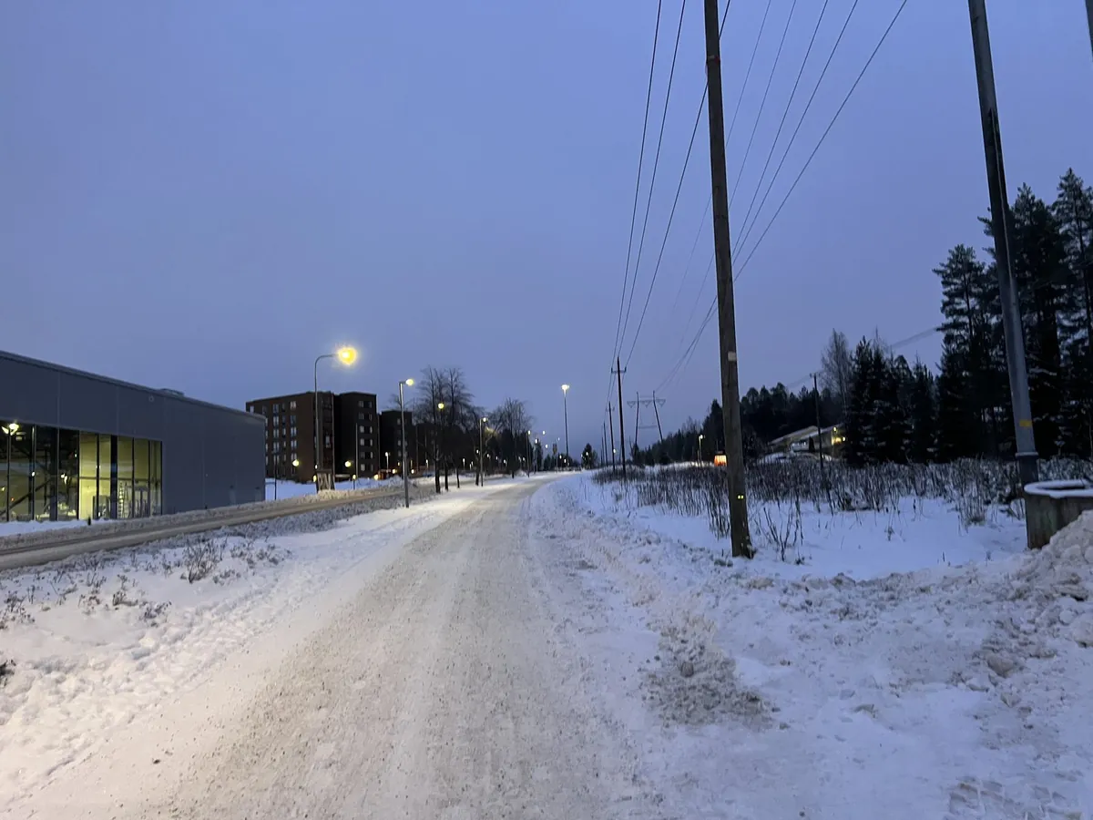 夕暮れの雪道と、街灯の灯る北国の一本道
