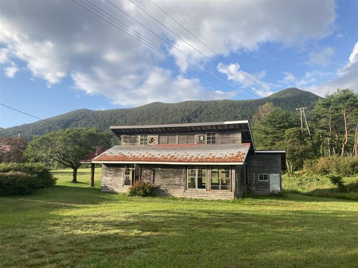 山を背にした草原に建つ石積みの山小屋