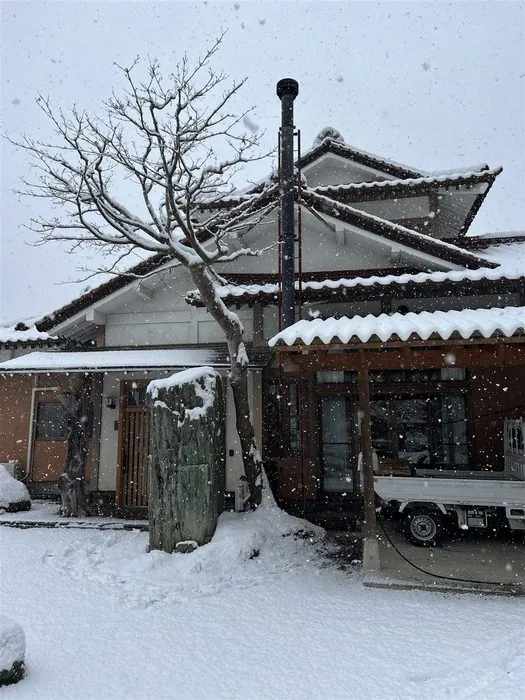 雪の降る日、岩手の家の屋根に立つ薪ストーブの煙突