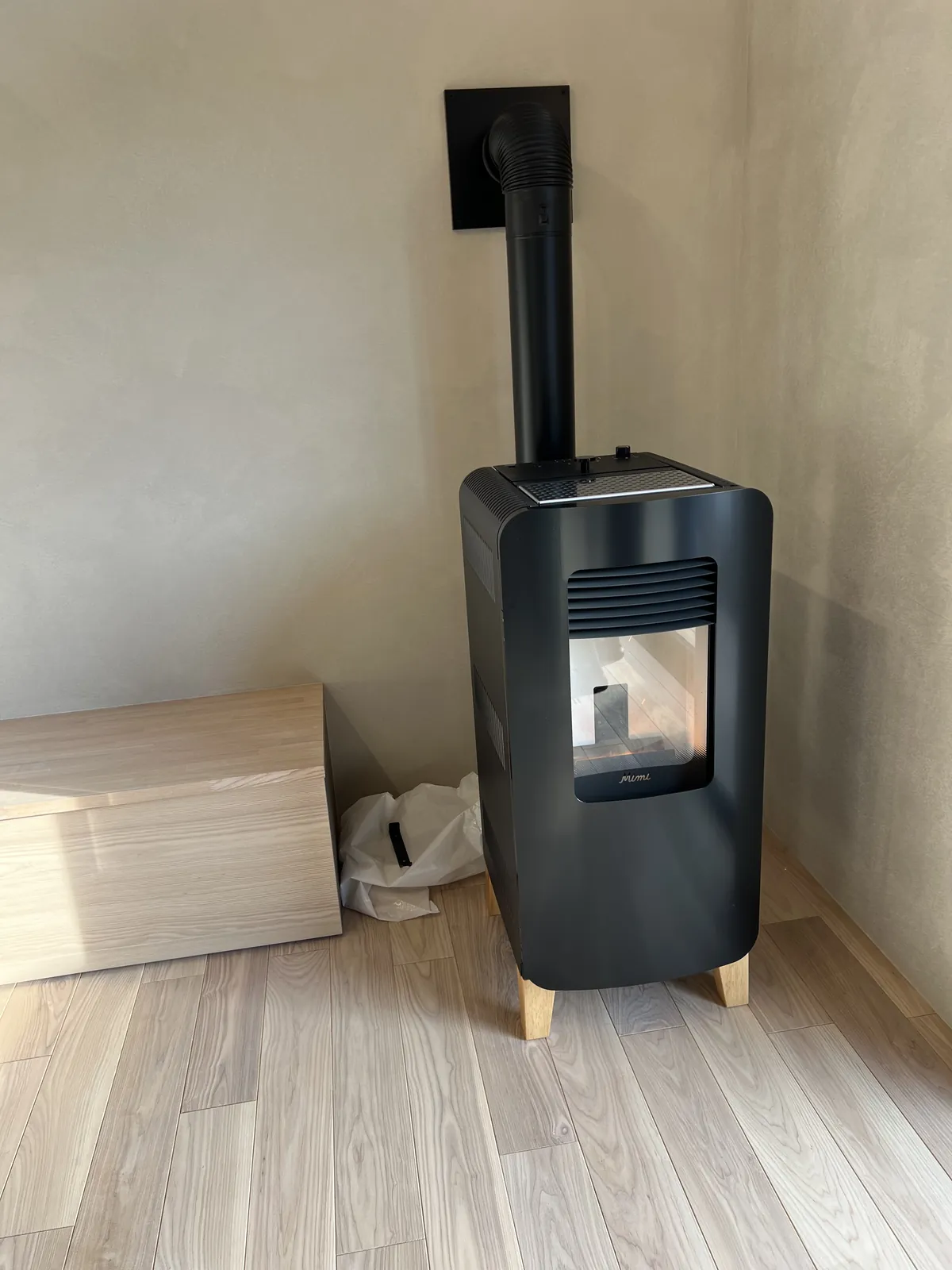 一戸町の住宅に設置したトヨトミ PE-6。木の脚の黒いボディ。壁の給排気口から配管をつないである