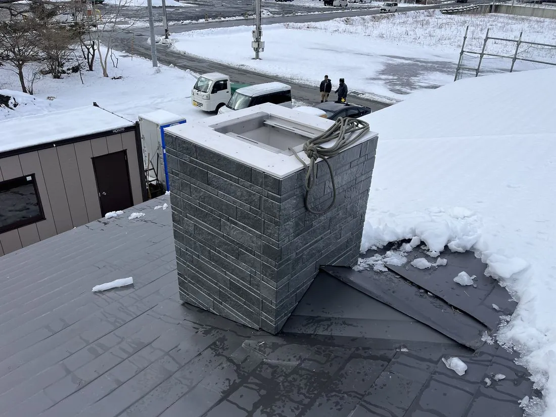 雪の屋根の上での煙突囲いの工事