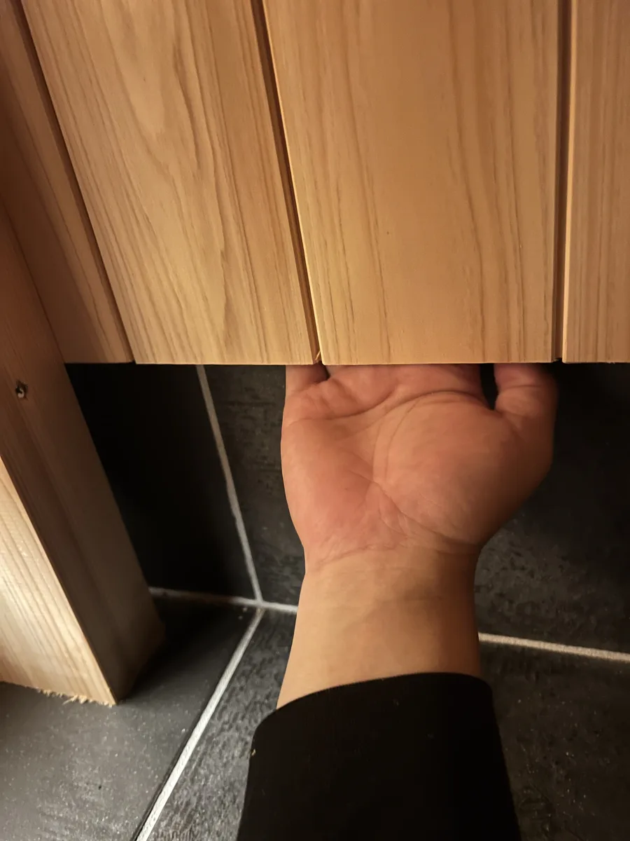仕上げた羽目板の裏へ手を差し入れる。壁の中に通気層が通っていることが分かる