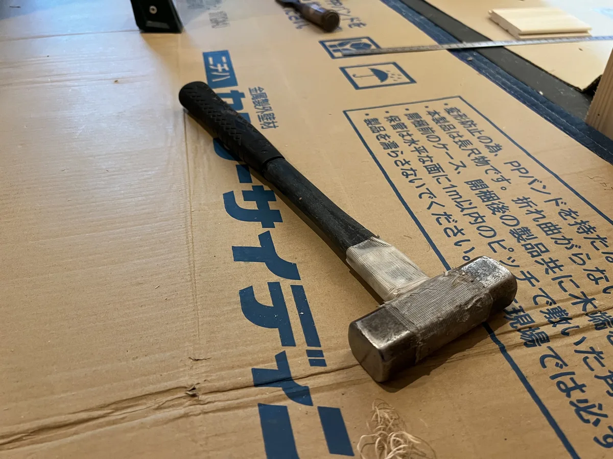 養生の上に置かれた玄能と木片。サウナ室の造作に使う手道具