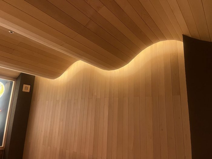 波打つ曲線を描く木の天井と壁。間接照明が陰影をつくる