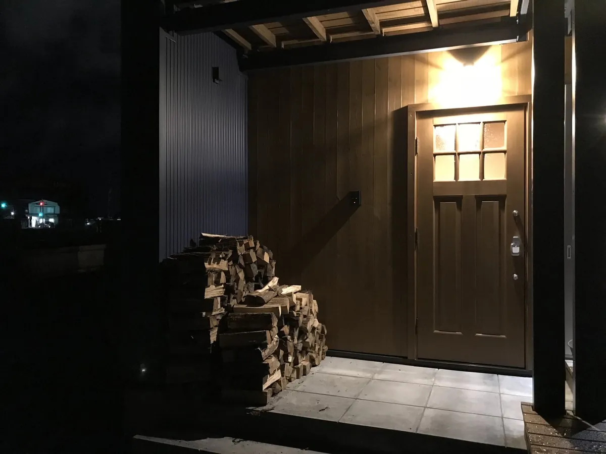 夜、お客様のお宅の玄関わきに積み上がった配達済みの薪