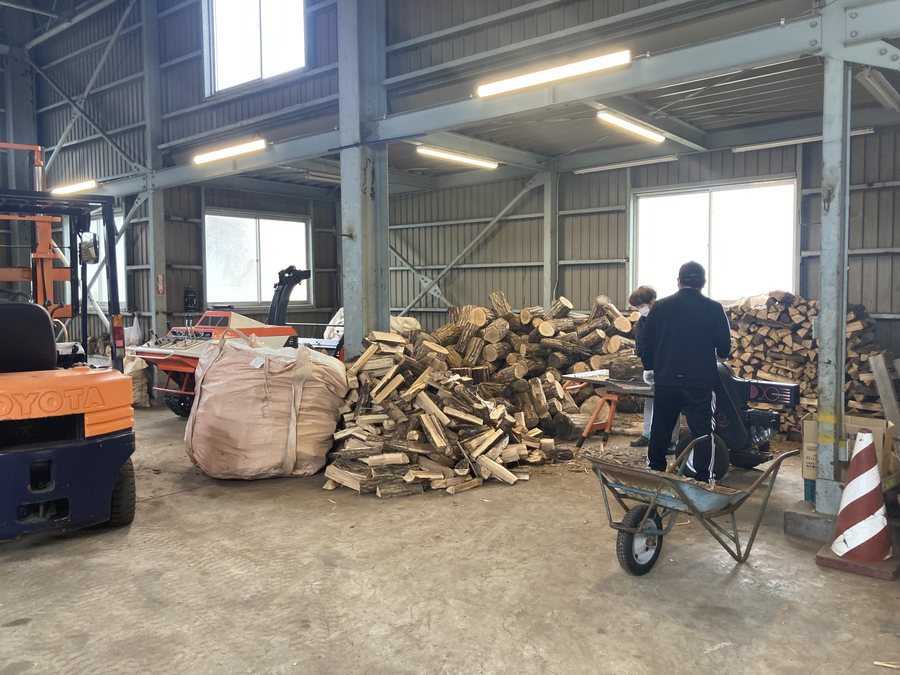 倉庫でフレコンバッグに薪を詰める出荷準備の作業風景