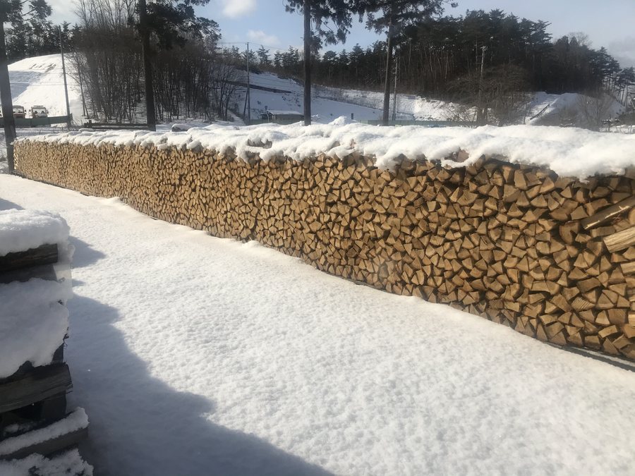 雪をかぶった薪の壁。冬に備えて積んだ乾燥薪