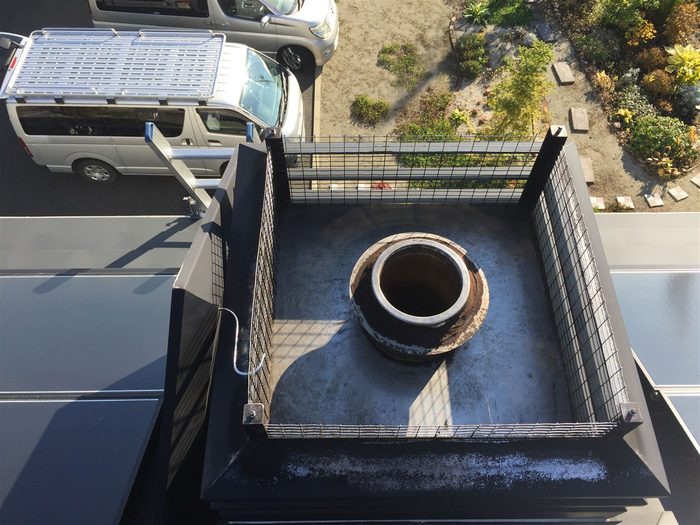 屋根の上での煙突トップ点検