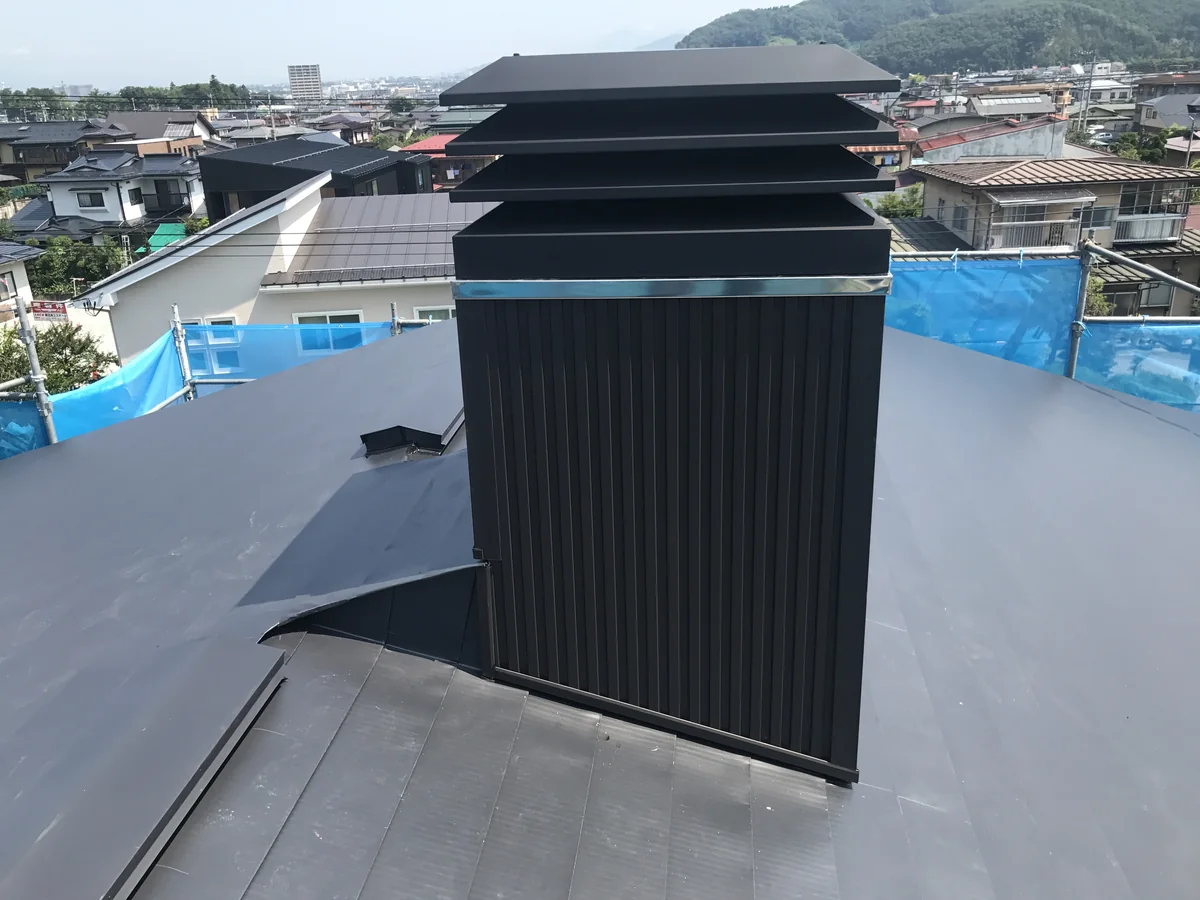 屋根の上に立てた、板金で囲った四角い煙突。笠木が段になっている