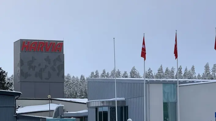 雪の森を背にして建つハルビアの本社。建物の上に赤いHARVIAの看板と社旗が並ぶ