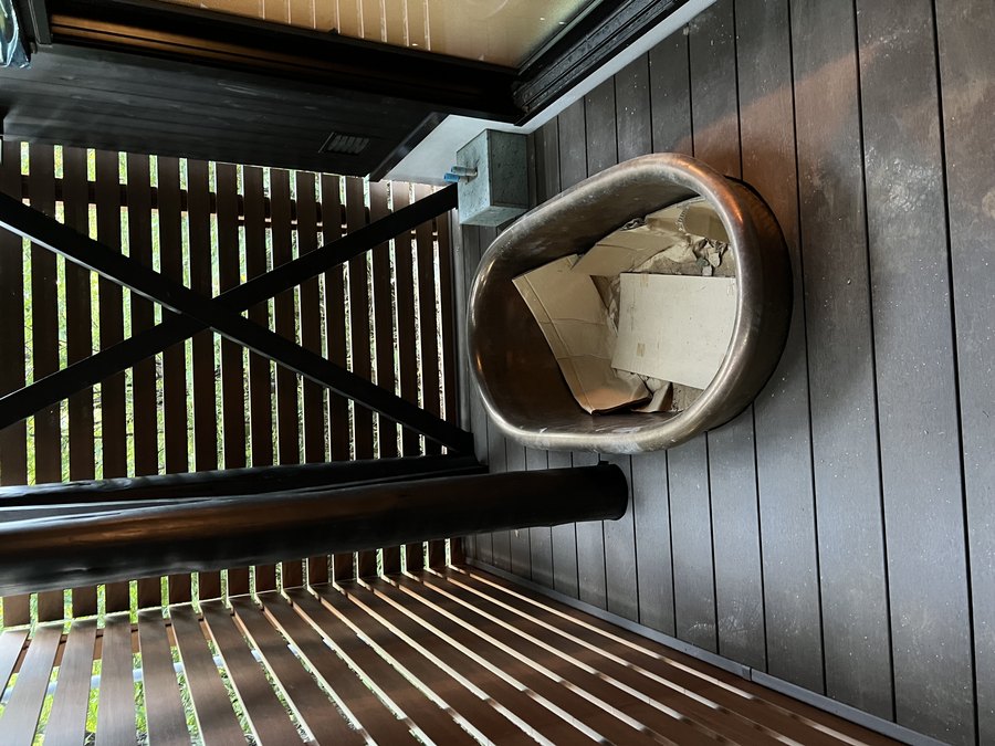 当社施工：黒い外壁のサウナ小屋の前、木のデッキに置かれた水風呂用のバスタブ