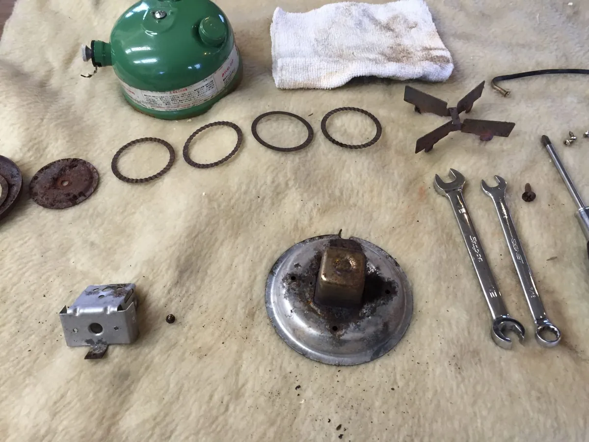 コールマンのストーブを全分解し、部品と工具を並べた作業台