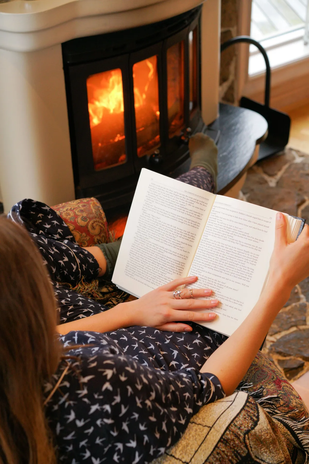 暖炉の焚き火のそばで本を読む女性