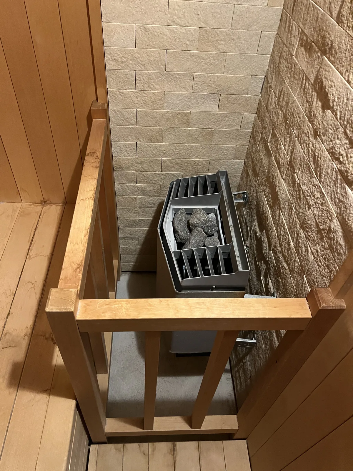 板張りのサウナ室に据えられた壁掛け式サウナヒーター。サウナストーンがしっかりと積まれている