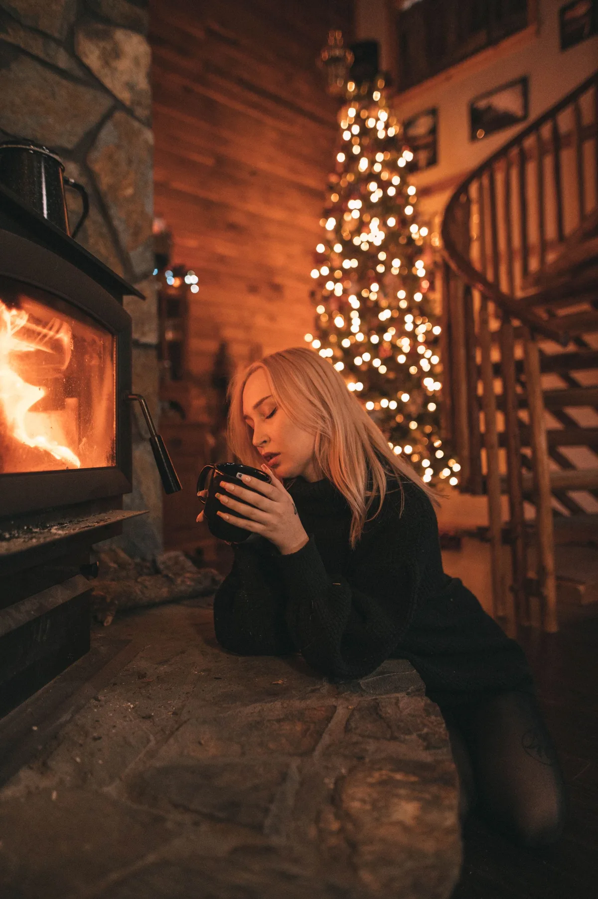 クリスマスツリーと暖炉そばの女性