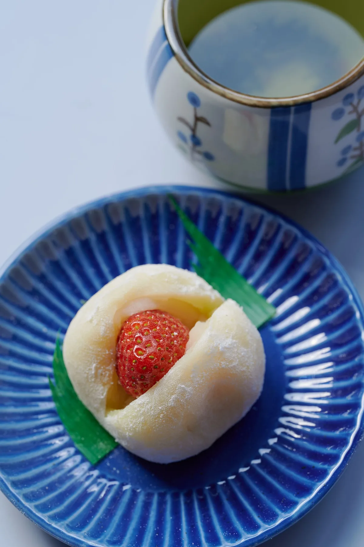 いちご大福と湯呑みを青い皿に盛った和菓子