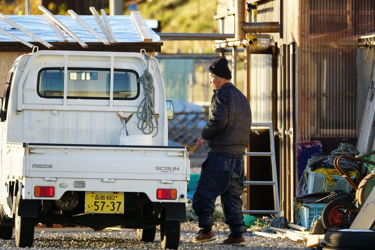 荷台のトラックで作業する老漁師