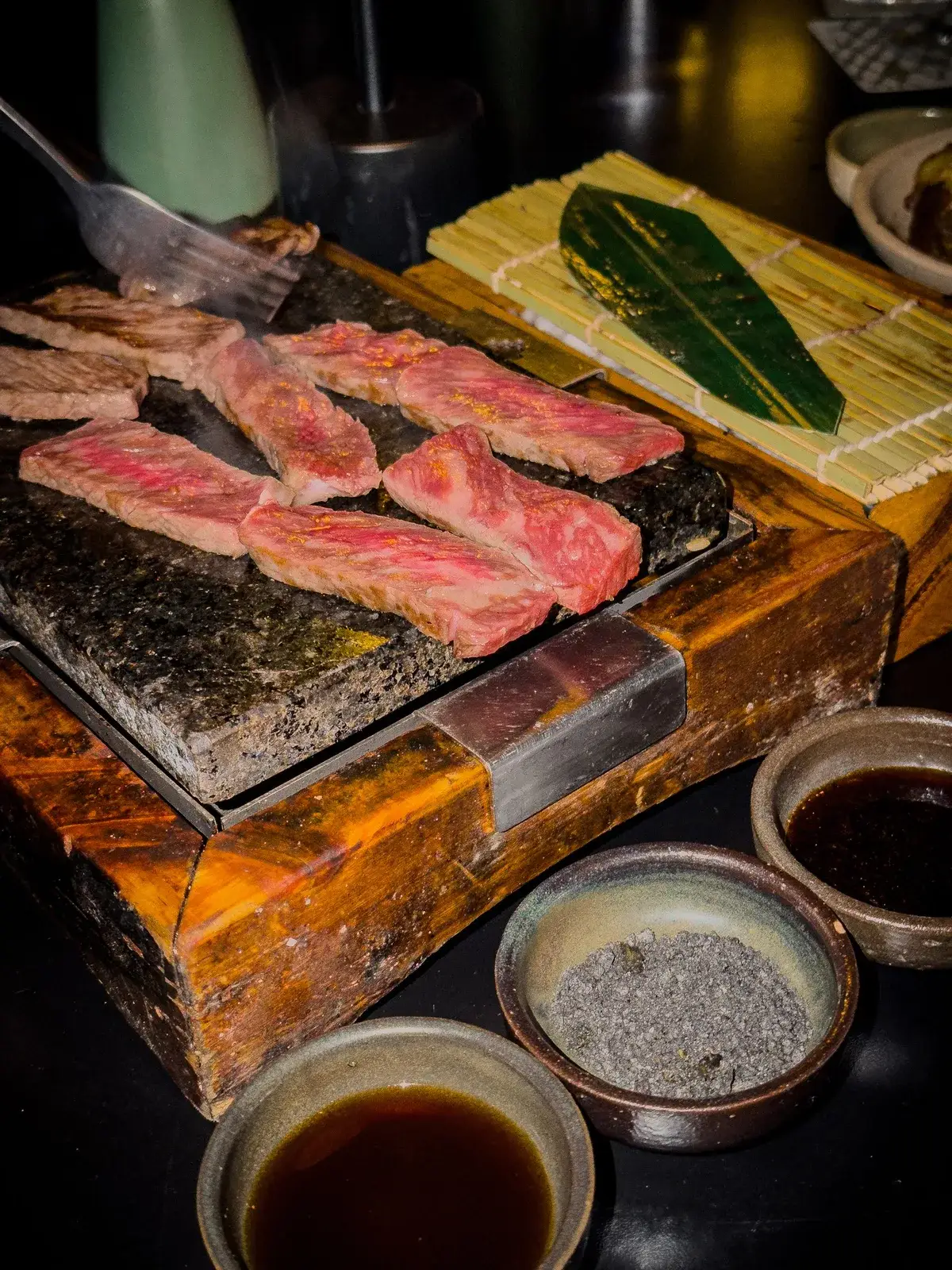 熱した石板の上で焼ける牛肉と和の調味料